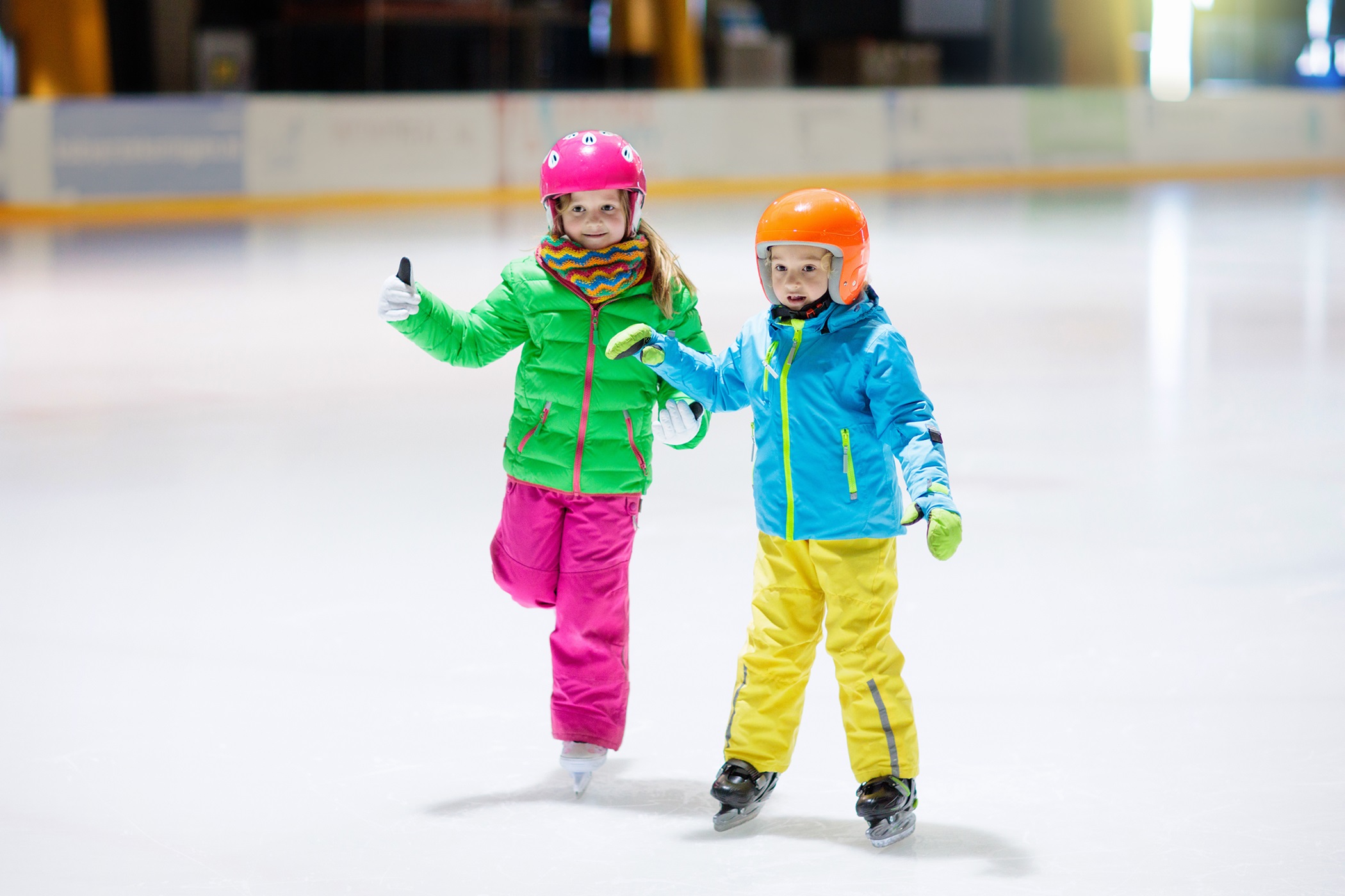 Twee kinderen zijn met plezier aan het schaatsen op de schaatsbaan van Optisport.