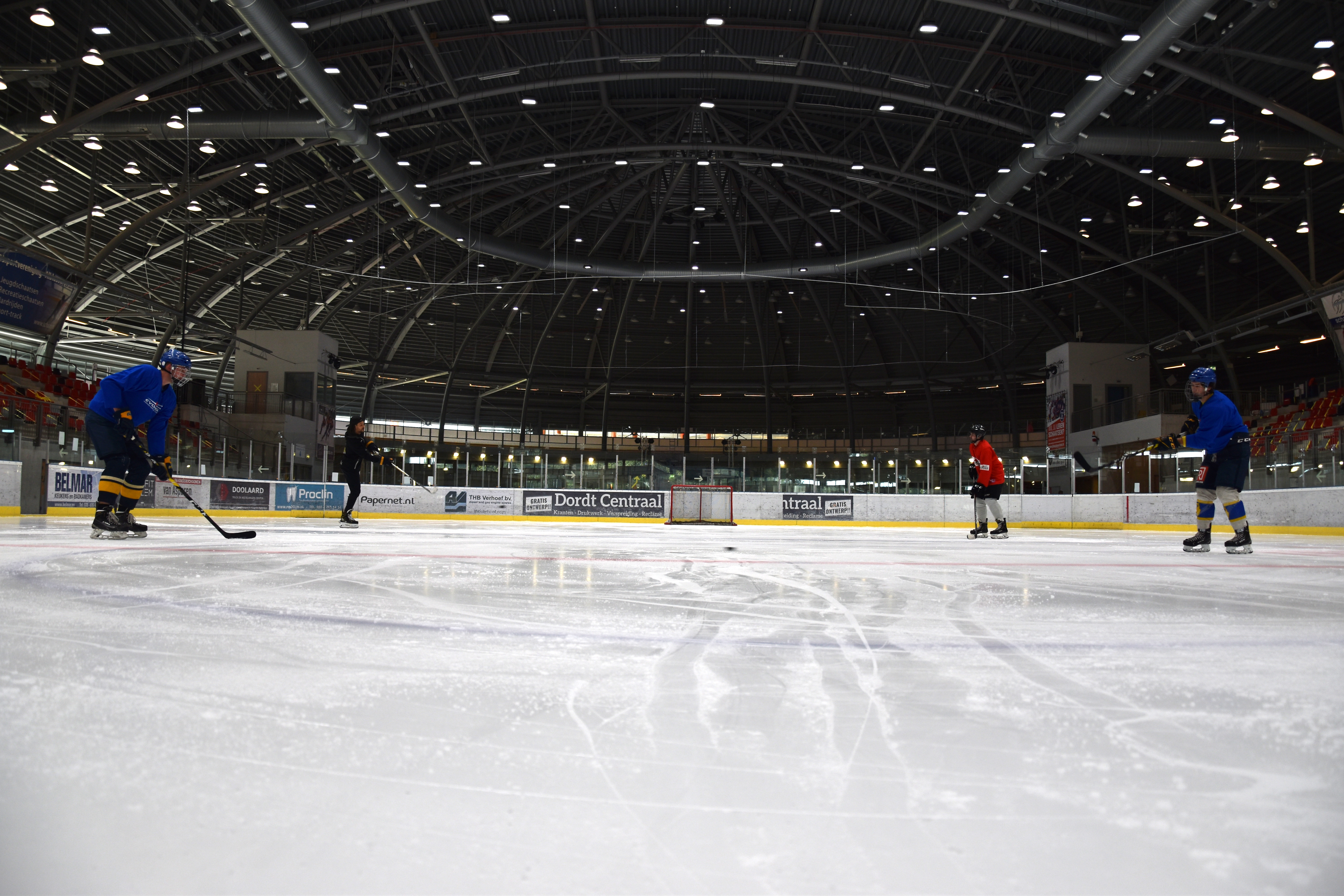 Vier mensen spelen naar elkaar over op het tijdens de ijshockey les.